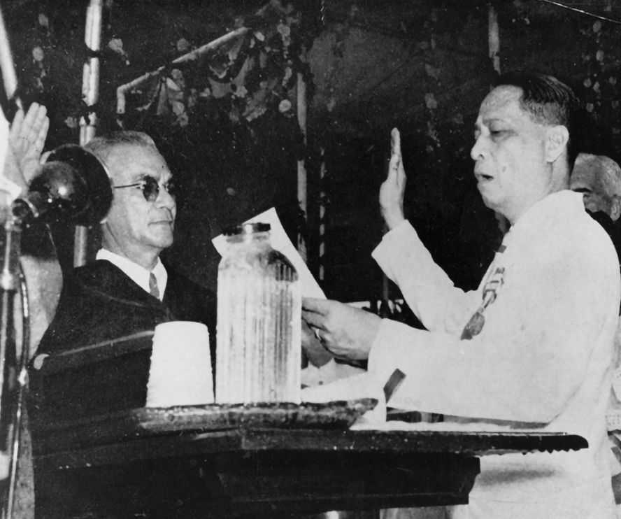 Black and white photo of President Manuel Roxas speaking over a podium and holding his right hand up in oath