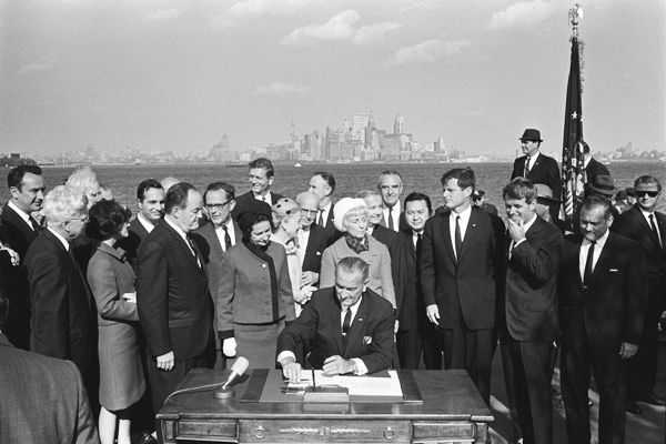 Lyndon Johnson signs the immigration act with New York City in the background 